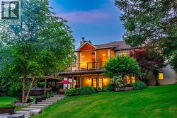 Rear view of property featuring a yard, a chimney, stairs, and a wooden deck - 