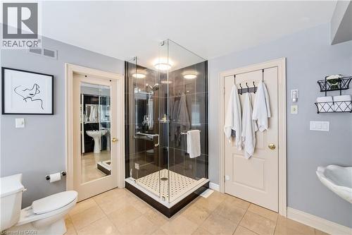 Primary bathroom with corner glass-enclosed shower featuring dark tile surround and white tiled pan, 2 separate white pedestal sinks - 7775 St. Augustine Crescent, Niagara Falls, ON 