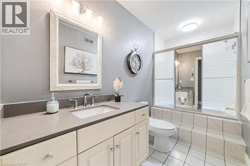Bathroom featuring a neutral palette, a white vanity with a light gray countertop, an integrated sink with a chrome faucet, and a large mirror with an ornate white frame - 7775 St. Augustine Crescent, Niagara Falls, ON 