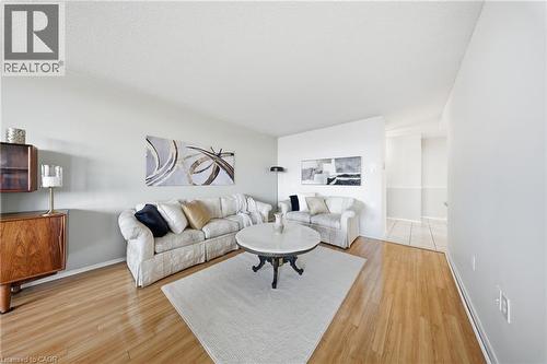 Spacious living area featuring wood-finish flooring, light-toned walls, and a textured ceiling - 2055 Upper Middle Road Unit# 602, Burlington, ON 