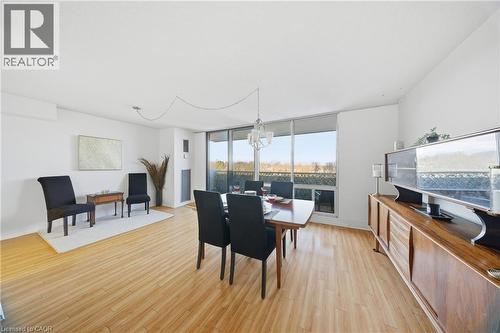 Expansive living area featuring light wood-finish flooring, white walls, and a large window with a distant landscape - 2055 Upper Middle Road Unit# 602, Burlington, ON 