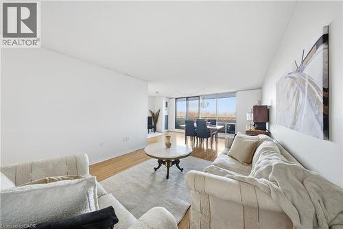 Open concept living area featuring wood-finish flooring, white walls, and a large window wall - 2055 Upper Middle Road Unit# 602, Burlington, ON 