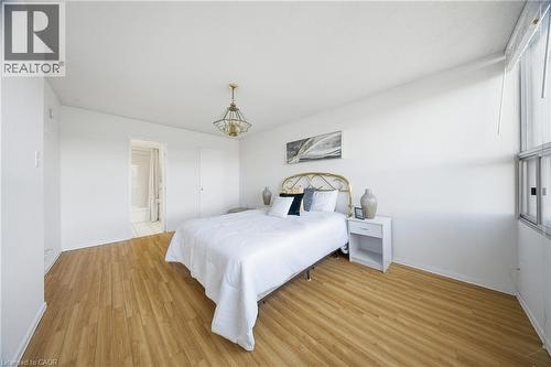 Bright room featuring wood-finish flooring, a contemporary ceiling light fixture, and a large window - 2055 Upper Middle Road Unit# 602, Burlington, ON 