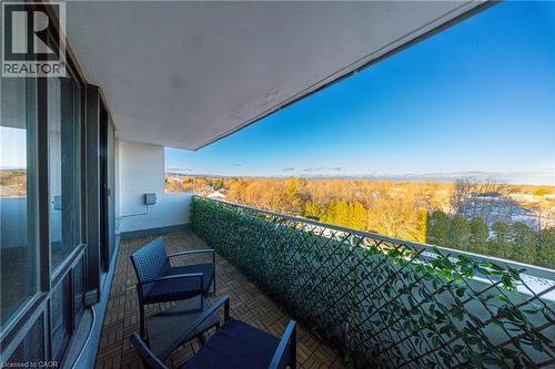 Private balcony featuring a wood-finish tile floor, full-height glass sliding doors, a decorative privacy screen, and an expansive natural landscape - 2055 Upper Middle Road Unit# 602, Burlington, ON 
