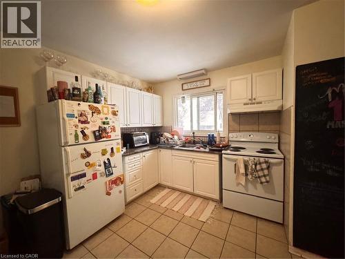 Kitchen with white cabinetry, tile flooring, a window above the sink, and a tile backsplash - 105 Marshall Street, Waterloo, ON 