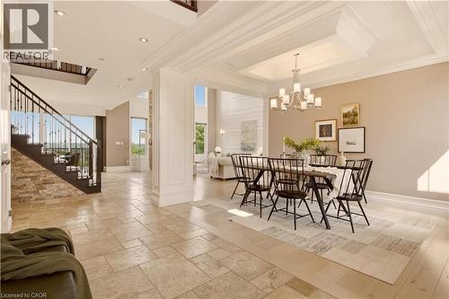 Spacious entry foyer featuring large format tile flooring, a dark wood staircase with wrought iron balusters, and a stone accent wall - 15 Mcwilliams Court, Cambridge, ON - Indoor Photo Showing Dining Room