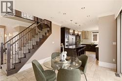 Open-concept living area featuring a grand staircase with dark wood newel posts and iron balusters, recessed lighting, and crown molding - 