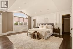 Spacious room featuring dark wood-finish flooring and a vaulted ceiling with recessed lighting - 