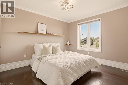 Spacious room featuring rich wood-finish flooring, a large window with white trim, and a contemporary ceiling light fixture - 15 Mcwilliams Court, Cambridge, ON - Indoor Photo Showing Bedroom