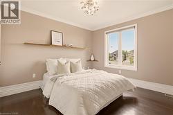 Spacious room featuring rich wood-finish flooring, a large window with white trim, and a contemporary ceiling light fixture - 