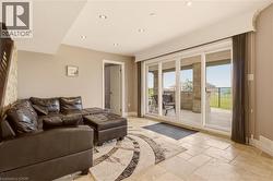 Recessed lighting illuminates the space, featuring a stone accent wall, light-toned wall paint, and a sliding glass door system - 