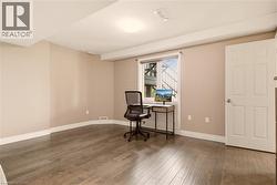 Spacious room featuring wood-finish flooring, neutral wall tones, a large window, and a paneled door - 