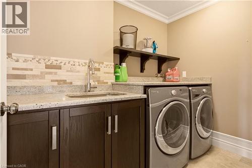 Utility area featuring a stainless steel sink, light-toned countertop, and dark wood-finish cabinetry - 15 Mcwilliams Court, Cambridge, ON - Indoor Photo Showing Laundry Room