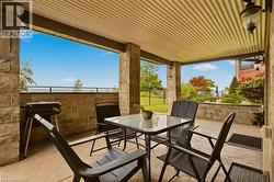 Covered patio featuring stone pillars and wall, corrugated ceiling, and concrete flooring - 
