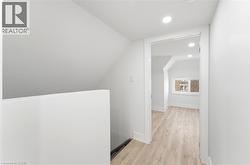 Recessed lighting illuminates wood-finish flooring throughout this bright space, featuring white walls and trim - 