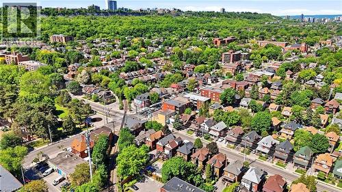 Aerial perspective showcasing a residential neighborhood with diverse housing styles, mature trees, and a tree-lined escarpment in the background - 968 Main Street E, Hamilton, ON 