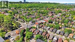 Aerial perspective showcasing a residential neighborhood with diverse housing styles, mature trees, and a tree-lined escarpment in the background - 