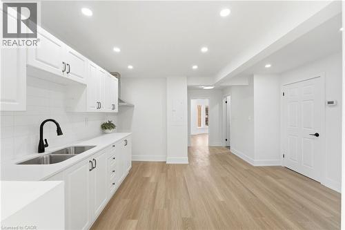 Modern kitchen featuring white shaker cabinetry, stainless steel double-basin sink with matte black faucet, and white subway tile backsplash - 968 Main Street E, Hamilton, ON 