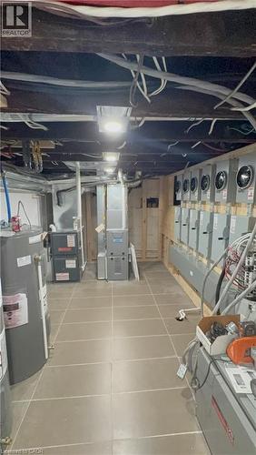 Utility room featuring multiple electrical panels, two water heaters, and two furnaces - 968 Main Street E, Hamilton, ON - Indoor Photo Showing Other Room