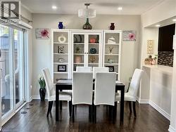 Dining area featuring wood-finish flooring, white built-in shelving, a modern ceiling light fixture, and a sliding glass door - 