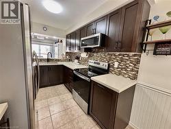 Contemporary kitchen featuring dark wood-finish cabinetry, light-toned countertops, and a mosaic tile backsplash - 