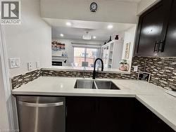 Kitchen featuring light-toned countertops, dark cabinetry, and a mosaic tile backsplash - 