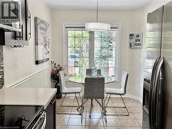 Bright kitchen dining area featuring a large window, tiled flooring, pendant lighting, beadboard wainscoting, and stainless steel appliances - 