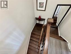 Hardwood staircase featuring dark wood treads, white risers, and a wood-finish handrail with black iron balusters - 