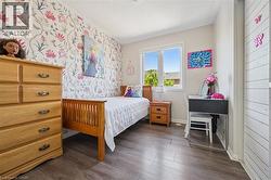 Wood-finish flooring throughout, complemented by a floral patterned accent wall and a white trim window - 