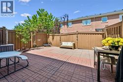 Private backyard featuring brick paver patio, wood fencing, and mature trees - 