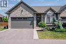 Stone facade residence featuring an attached garage with panel detailing, a paved driveway, and mature landscaping - 15 Winterberry Lane, Waterford, ON 