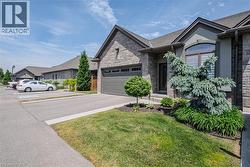 Stone and stucco exterior featuring an attached garage, arched window, and mature landscaping - 