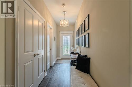 Welcoming entryway featuring dark wood-finish flooring, light tan wall paint, and white trim - 15 Winterberry Lane, Waterford, ON 