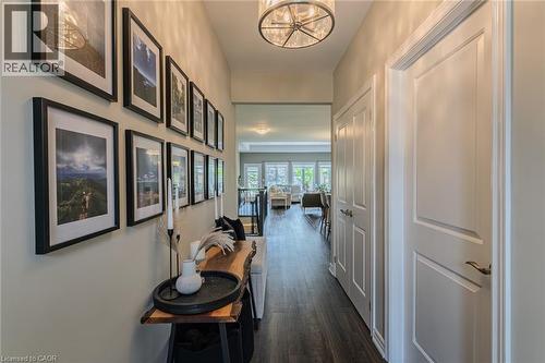 Hallway featuring wood-finish flooring and a contemporary drum pendant light fixture - 15 Winterberry Lane, Waterford, ON 