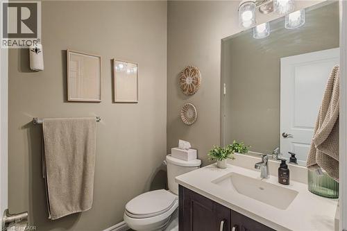 Bathroom featuring a dark wood-finish vanity with a light-toned countertop, an integrated rectangular sink, a chrome faucet, and a large wall-mounted mirror - 15 Winterberry Lane, Waterford, ON 
