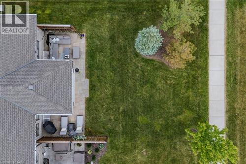 Expansive green lawn with mature landscaping, a concrete sidewalk, and two distinct patio areas featuring paver stones - 15 Winterberry Lane, Waterford, ON 