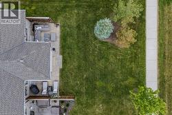 Expansive green lawn with mature landscaping, a concrete sidewalk, and two distinct patio areas featuring paver stones - 