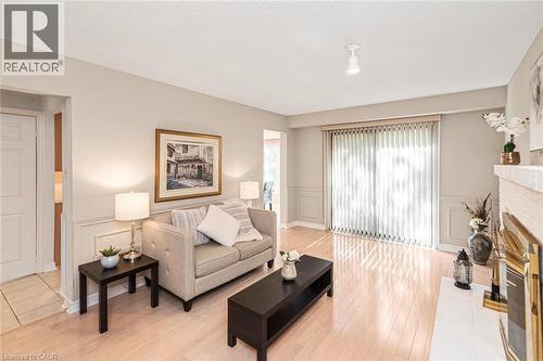 Bright living space featuring wood-finish flooring, a fireplace, and wainscoting detailing - 85 Citation Crescent, Ancaster, ON 