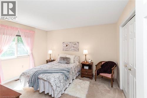 Carpeted room featuring a window with sheer pink curtains, neutral-toned walls, and a white bi-fold closet door - 85 Citation Crescent, Ancaster, ON 