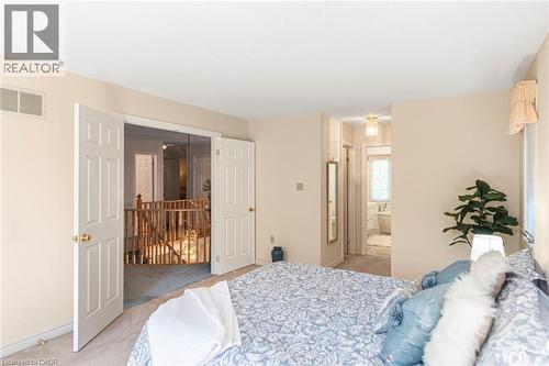 Carpeted room with a wide doorway offering access to a hallway and a second open doorway leading to a bathroom featuring a freestanding tub - 85 Citation Crescent, Ancaster, ON 