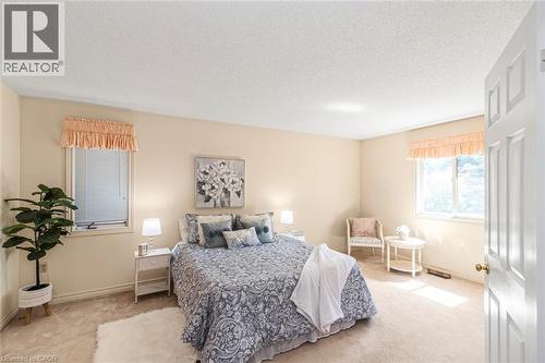Carpeted bedroom featuring two windows with horizontal blinds, neutral wall paint, and white trim - 85 Citation Crescent, Ancaster, ON 