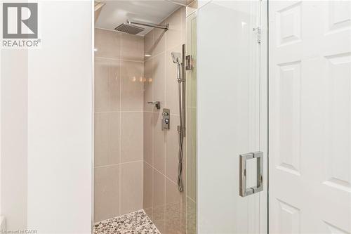 Glass-enclosed shower featuring large format wall tiles, a rain shower head, handheld shower fixture, and a mosaic tile floor - 85 Citation Crescent, Ancaster, ON 