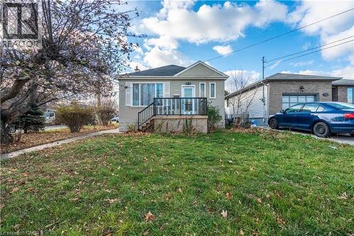 Single-story residence featuring a front porch with black railing, stucco facade, and a prominent front window with white shutters - 204 Glow Avenue Unit# Upper, Hamilton, ON 