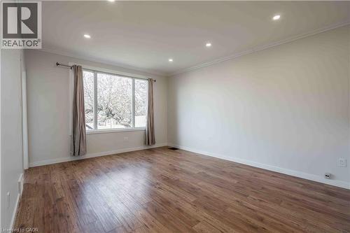Spacious interior room featuring wood-finish flooring, a large multi-pane window, recessed ceiling lighting, crown molding, and white baseboards - 204 Glow Avenue Unit# Upper, Hamilton, ON 