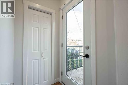 Full-lite exterior door with black hardware, flanked by a paneled bi-fold door - 204 Glow Avenue Unit# Upper, Hamilton, ON 