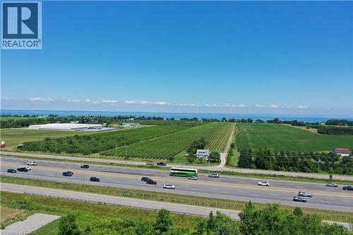 Expansive agricultural land featuring vineyards and fields, bordered by a highway and distant body of water - 3705 Service Road N, Beamsville, ON 