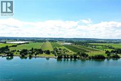 Expansive waterfront property featuring mature trees and a manicured lawn bordering the water - 