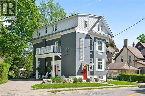 Multi-level residence featuring a gray exterior with white trim, a second-story balcony, and a prominent red front door - 149 Young Street, Kitchener, ON - Outdoor With Facade