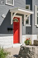 Red entry door with a sunburst transom window, sheltered by a white portico - 