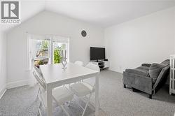 Bright interior space featuring a window with white sheers, light gray carpet, and white walls - 